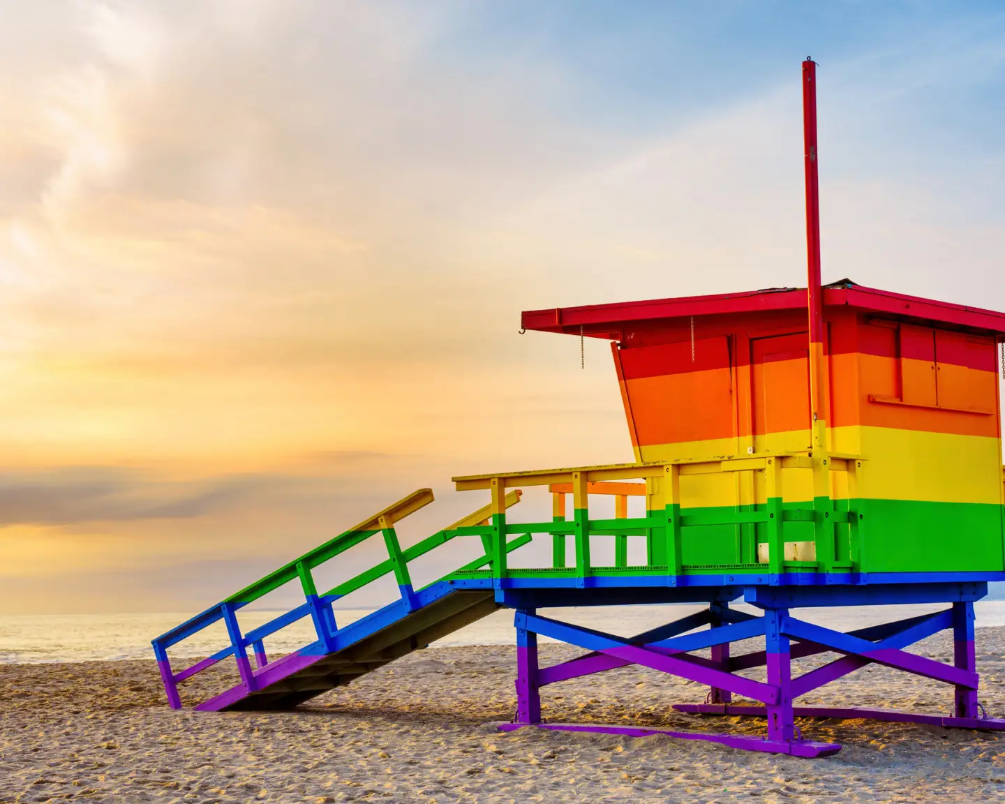 Regenbogenfarbener Rettungsturm am Strand von Los Angeles bei Sonnenuntergang.