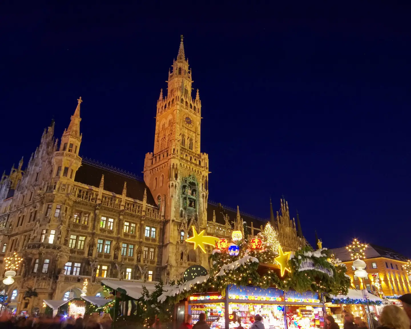 Festively lit Christkindlmarkt at Marienplatz in Munich with Christmas stalls and the New Town Hall in the background.