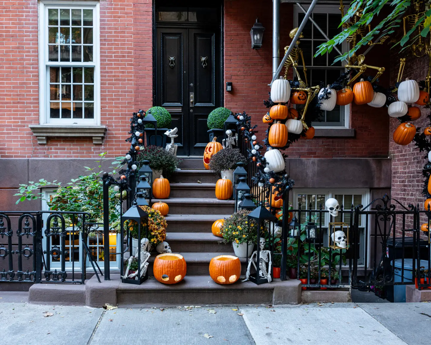 Halloween-Dekoration vor einem Stadthaus in New York mit Kürbissen, Skeletten und herbstlichem Schmuck.