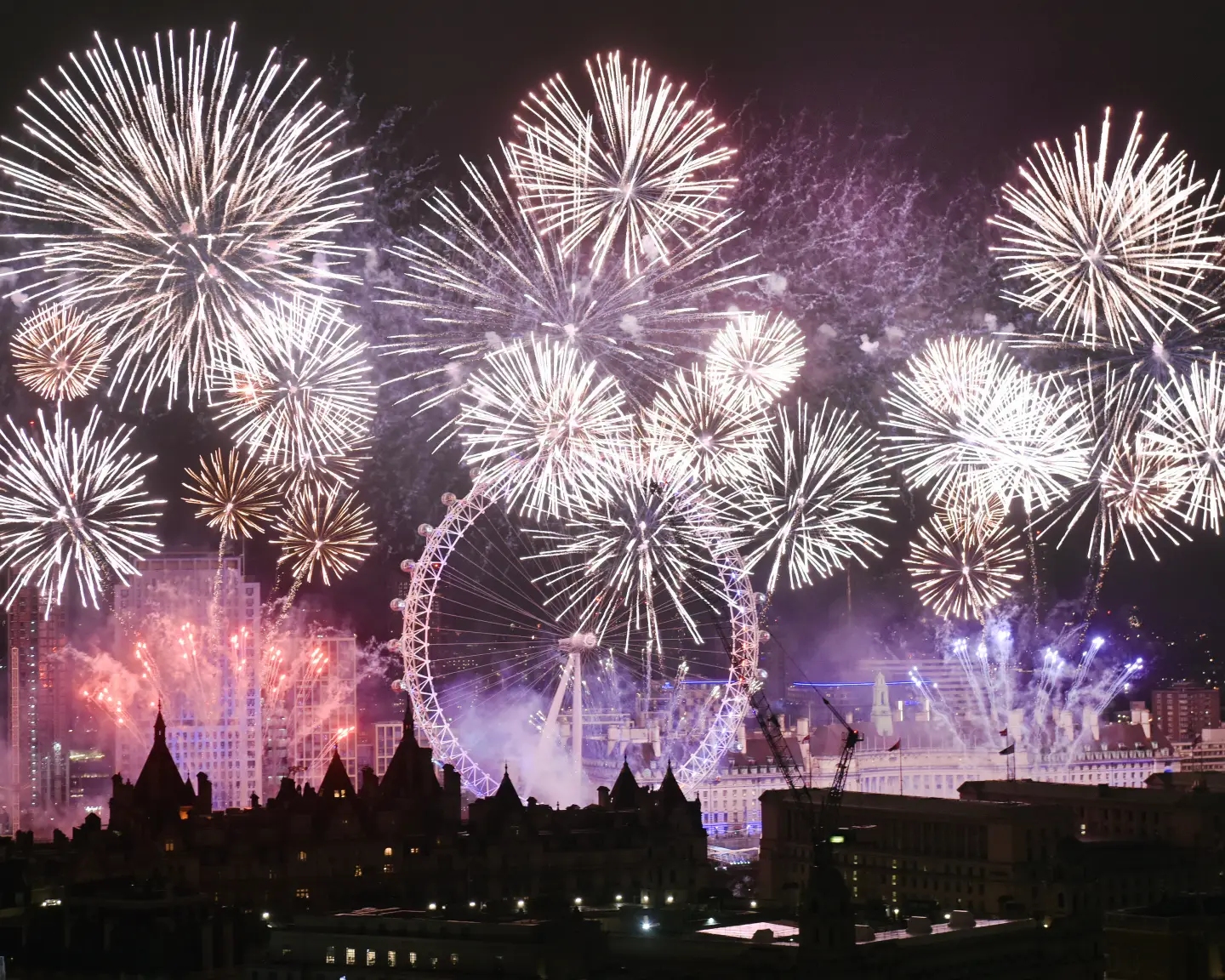 Großes Silvesterfeuerwerk über der Londoner Innenstadt mit dem beleuchteten London Eye im Zentrum.