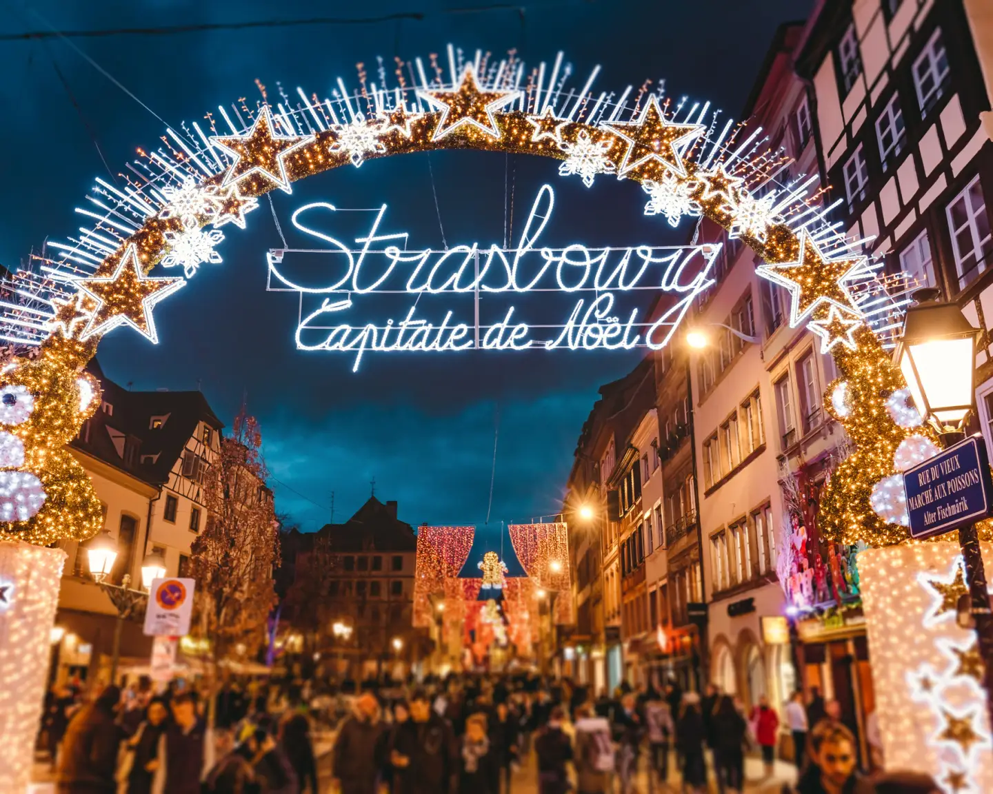 Festively lit street in Strasbourg with Christmas decorations and the lettering "Strasbourg Capitale de Noël" in the evening.