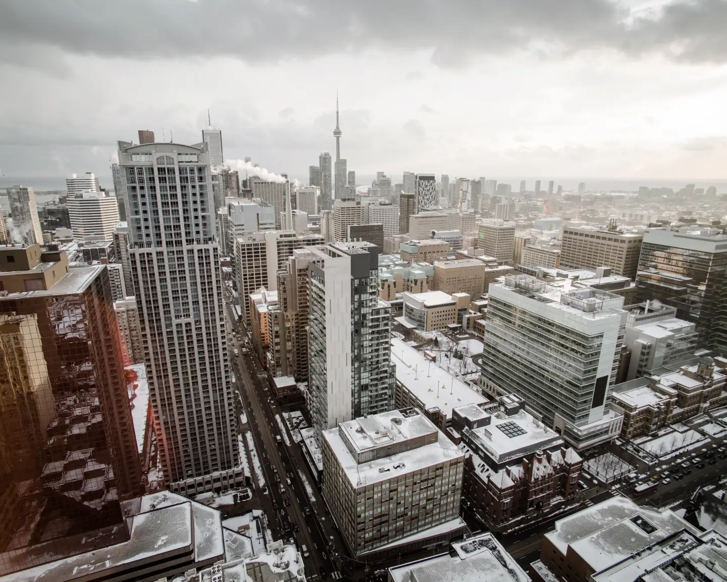 Winterlicher Blick über die Skyline von Toronto mit schneebedeckten Dächern und dem CN Tower im Hintergrund.