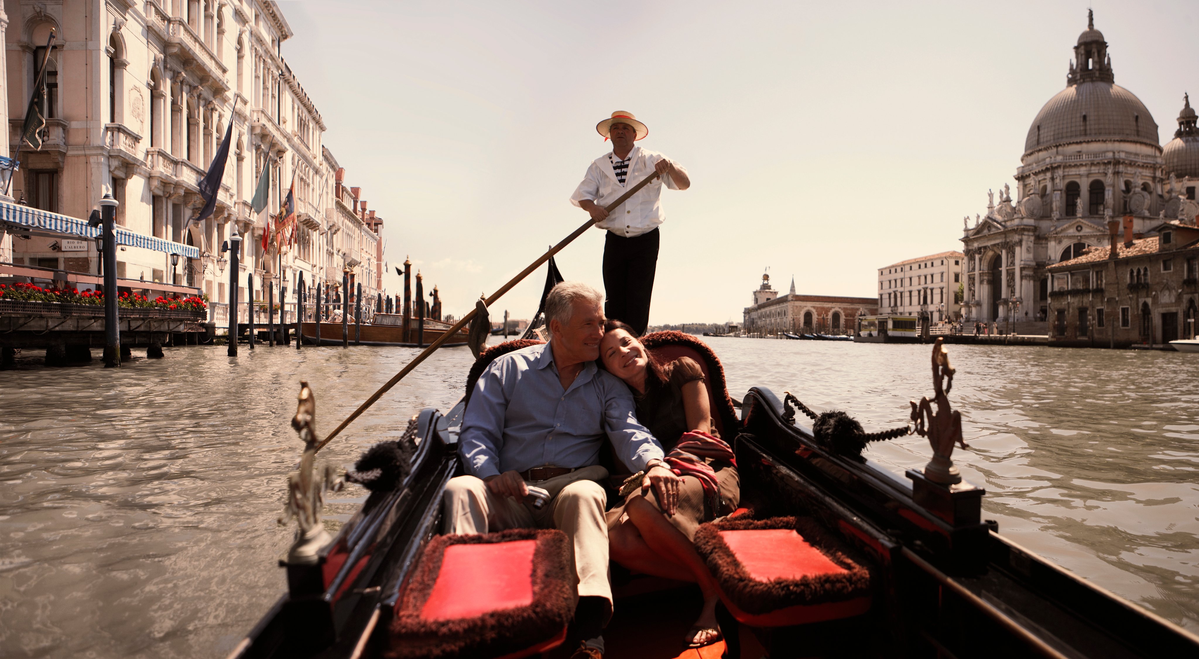 Paar genießt eine romantische Gondelfahrt auf dem Canal Grande in Venedig mit Basilika im Hintergrund.