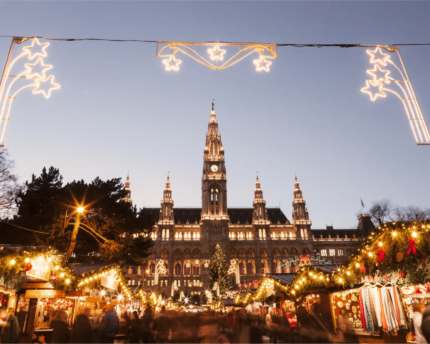 Festively lit Christmas market in front of Vienna City Hall with Christmas stalls and extensive Christmas lights in the evening.
