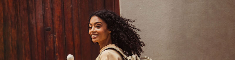 Girl with dark curly hair walking with an ice cream in her hand 