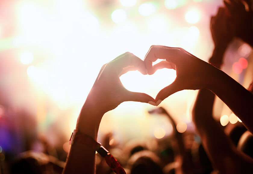 Best Party Cities in Europe Girl in a club in Europe raising her hands in a heart shape while enjoying a concent