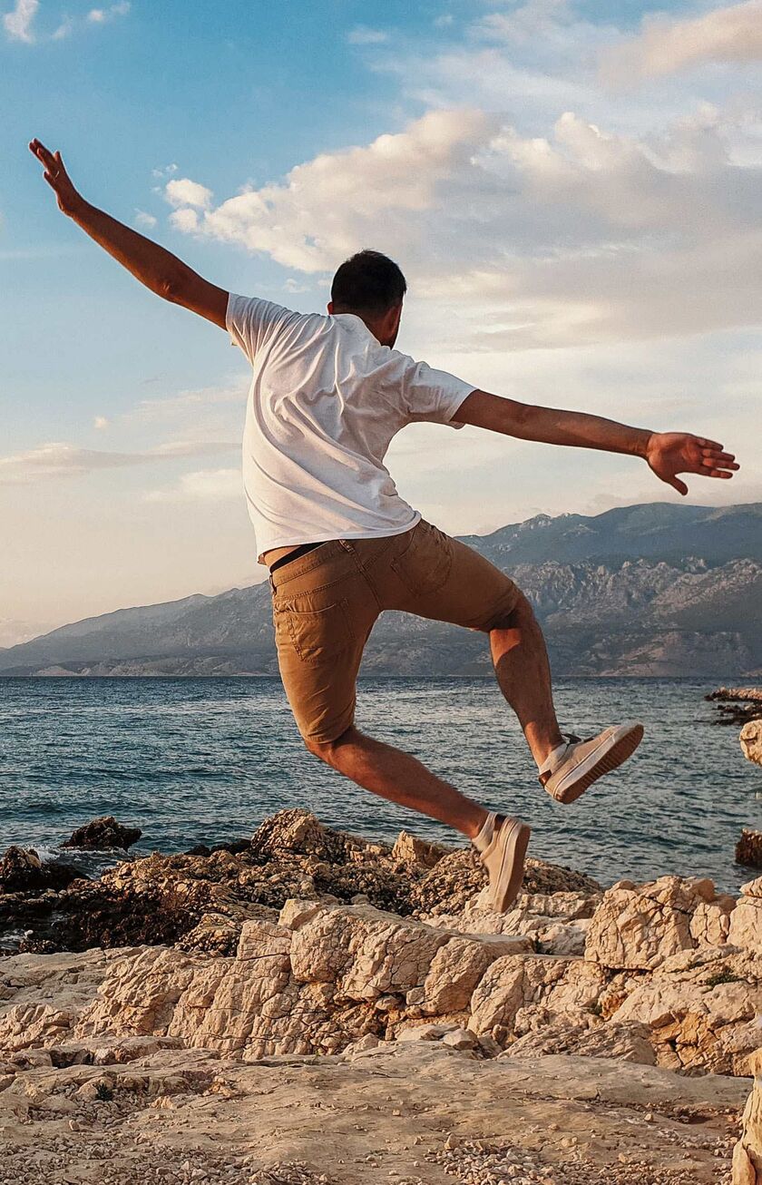 Happy man jumping for joy on the coast of Croatia