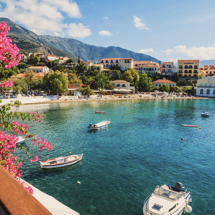 Die Bucht von Assos, ein Fischerdorf auf der Insel Kefalonia in Griechenland. Die Bucht ist von Klippen umgeben Es gibt eine Reihe von Booten und Fischernetzen im Wasser zu sehen.