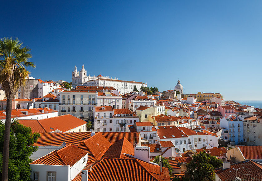 Flights to Lisbon View of the beautiful houses of Lisbon with the sea on the horizon.