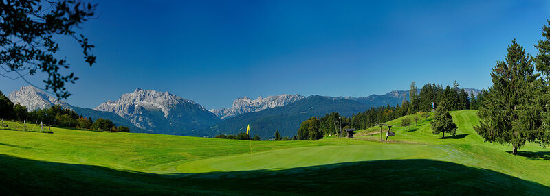 View of a golf course in Bavaria, Germany, with mountains in the background.
