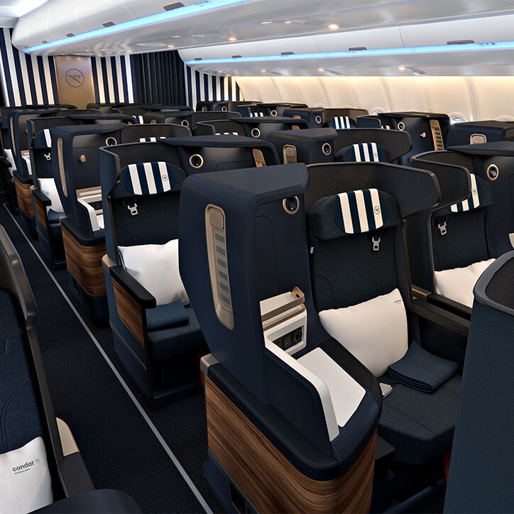 View of Condor's Business Class cabin with comfortable, fully reclining seats with white and dark blue striped headrests and white cushions.