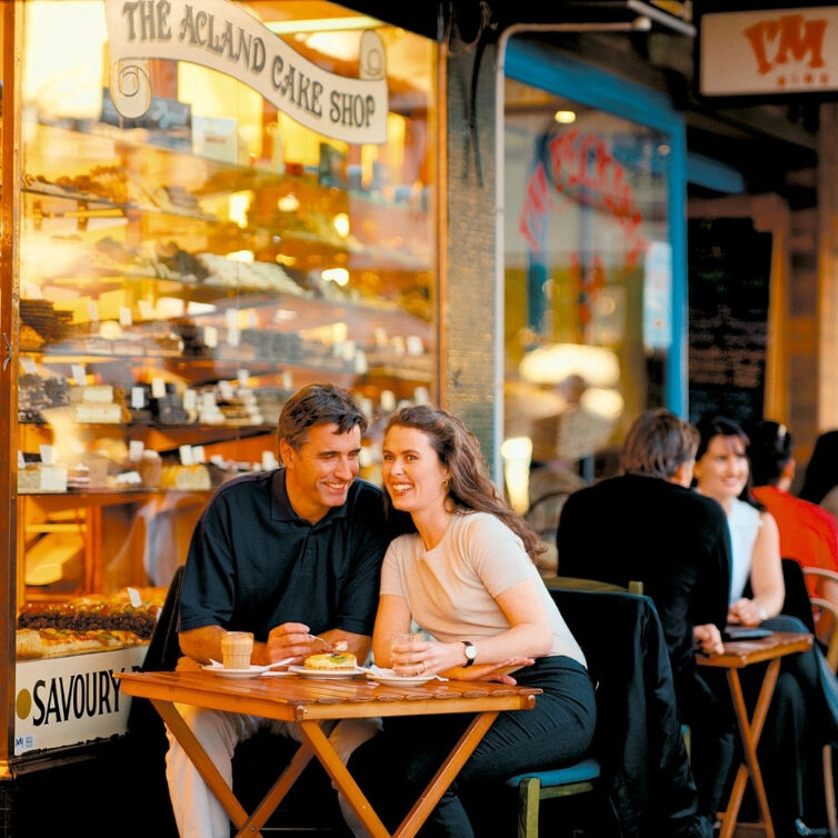  happy couple enjoying coffee and a sandwich at an outdoor table 