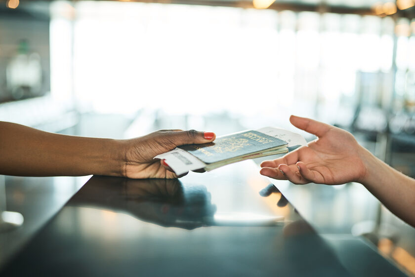 Step 01 – Document scan Close-up of hands exchanging a passport and boarding passes at airport check-in counte