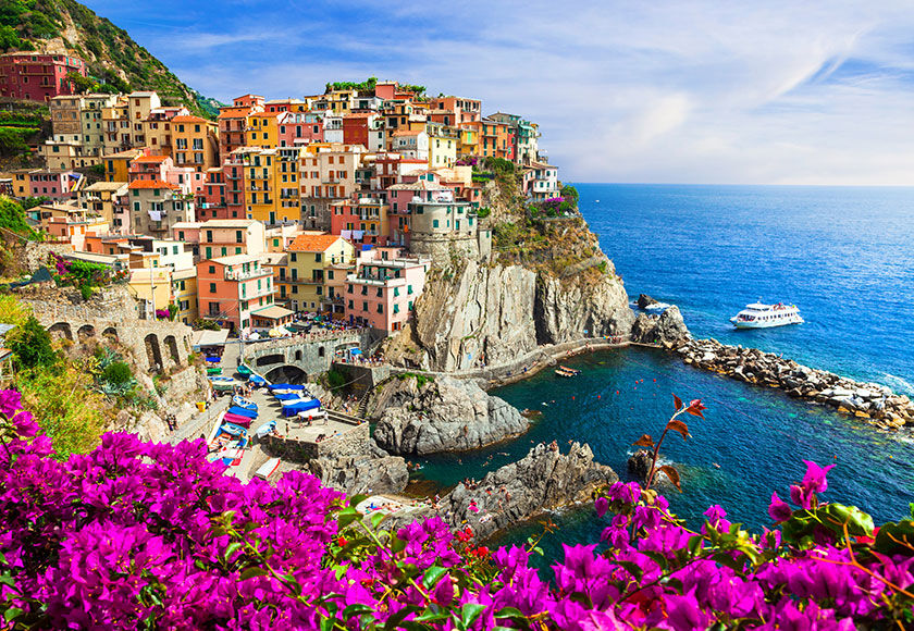 Nice view from a cliff with pink flowers of Manarola, Cinque Terre, Italy, with the sea in the background.