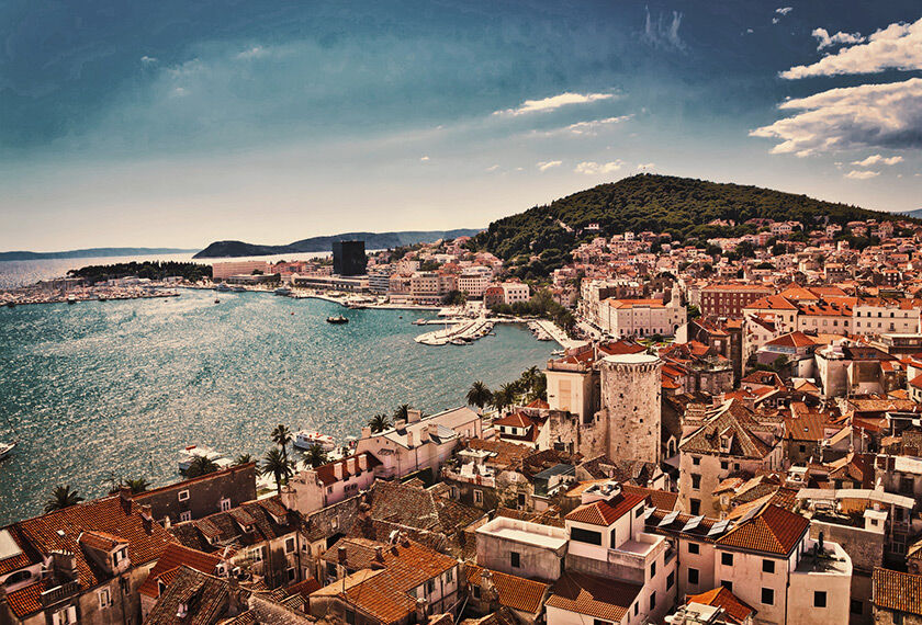  A panoramic view of Split, in Croatia, with terracotta roofs, set against a backdrop of a calm sea and a clear sky.