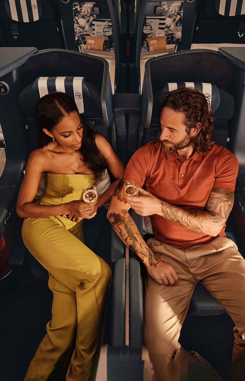 A couple is sitting in the Condor Business Class, enjoying a glass of champagne
