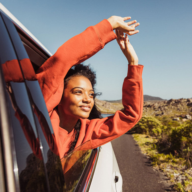 A woman laughing as she looks out of a car window.