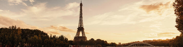  A panoramic view of the Eiffel Tower standing tall against a golden sunset sky in Paris.