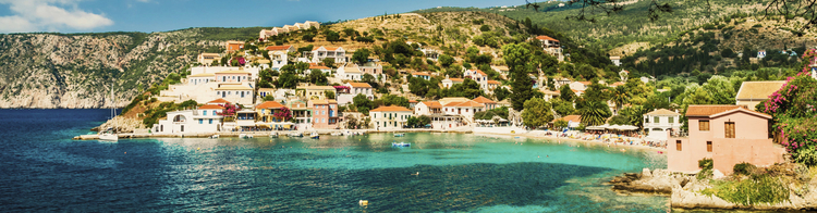 Blick auf das bunte Dorf Assos in Kefalonia, Griechenland. Man kann mehrere Gebäude mit terracottafarbenen Dächern und weißen Wänden sehen, die sich entlang der Küste erstrecken