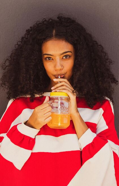 Woman in red and white striped jumper drinking juice.