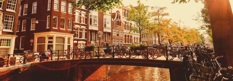 Amsterdam (AMS) View of a canal in Amsterdam with bicycles in a bridge