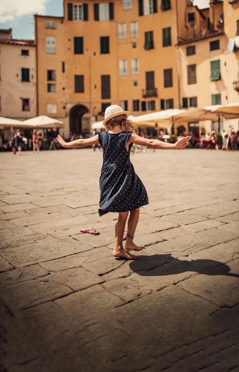 Little girl playing in a square with arches and traditional buildings in Italy