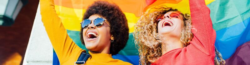 Two women holding a rainbow flag during Pride celebrations