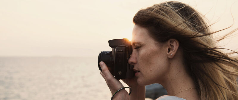 A woman takes a photo of the sea