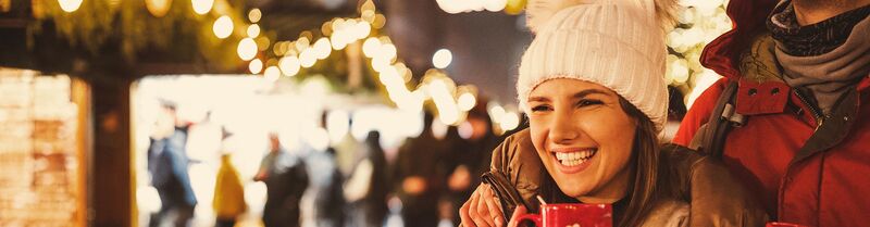 Woman laughing while drinking mullet wine at a Christmas market in Europe