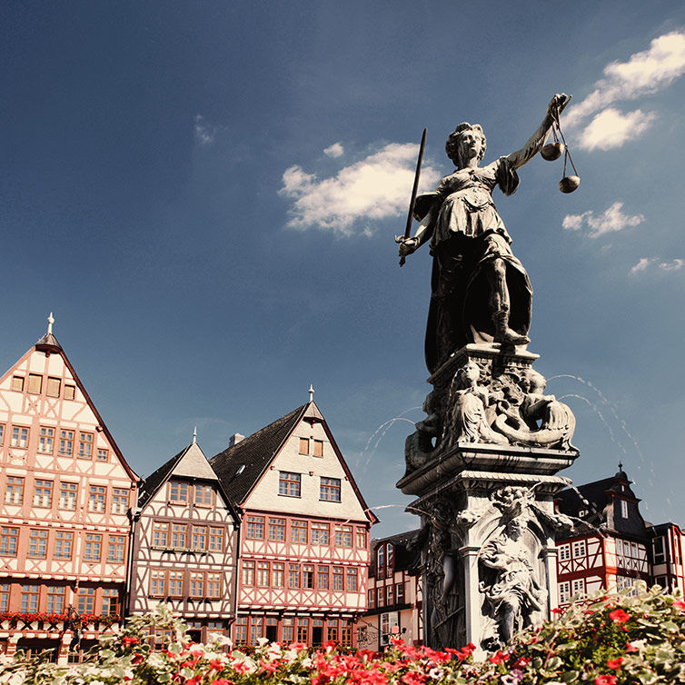 Statue at Römerplatz in Frankfurt, with a view of some of the historic facades of the square in the background.